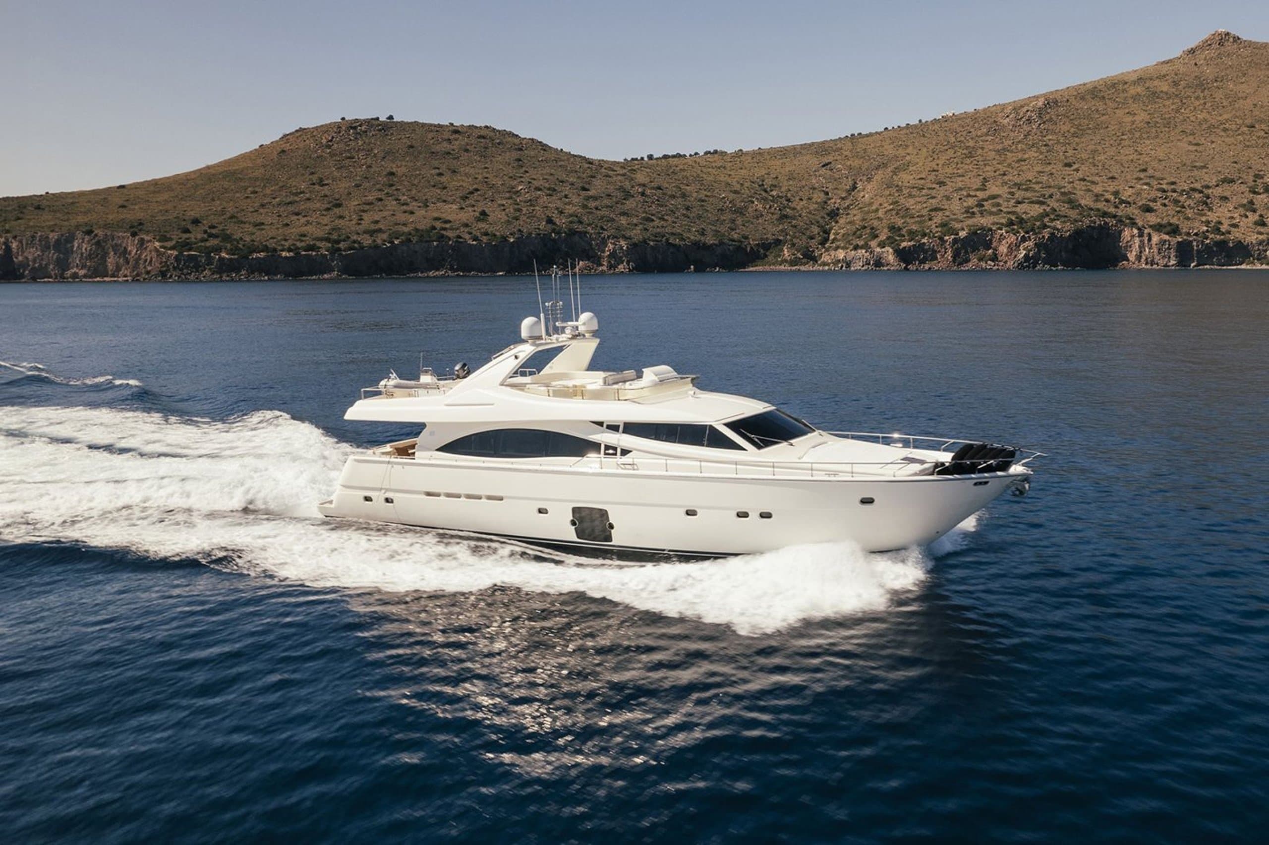 LIDIA - motor yacht underway with bow wake off a coastline | Drivas Yachts