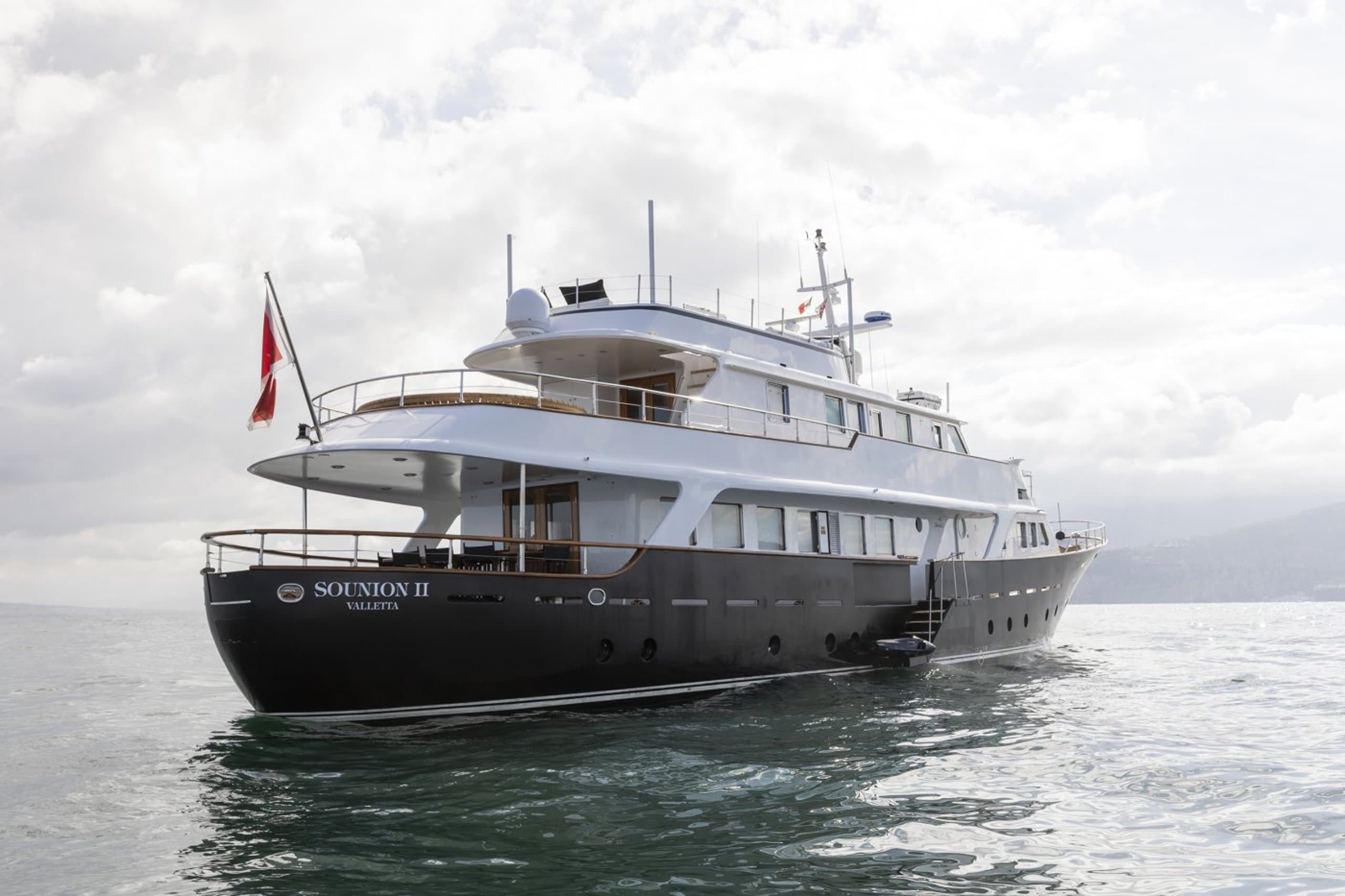 SOUNION II - profile view of the motor yacht with dark navy hull, name and Valletta home port on the transom | Drivas Yachts