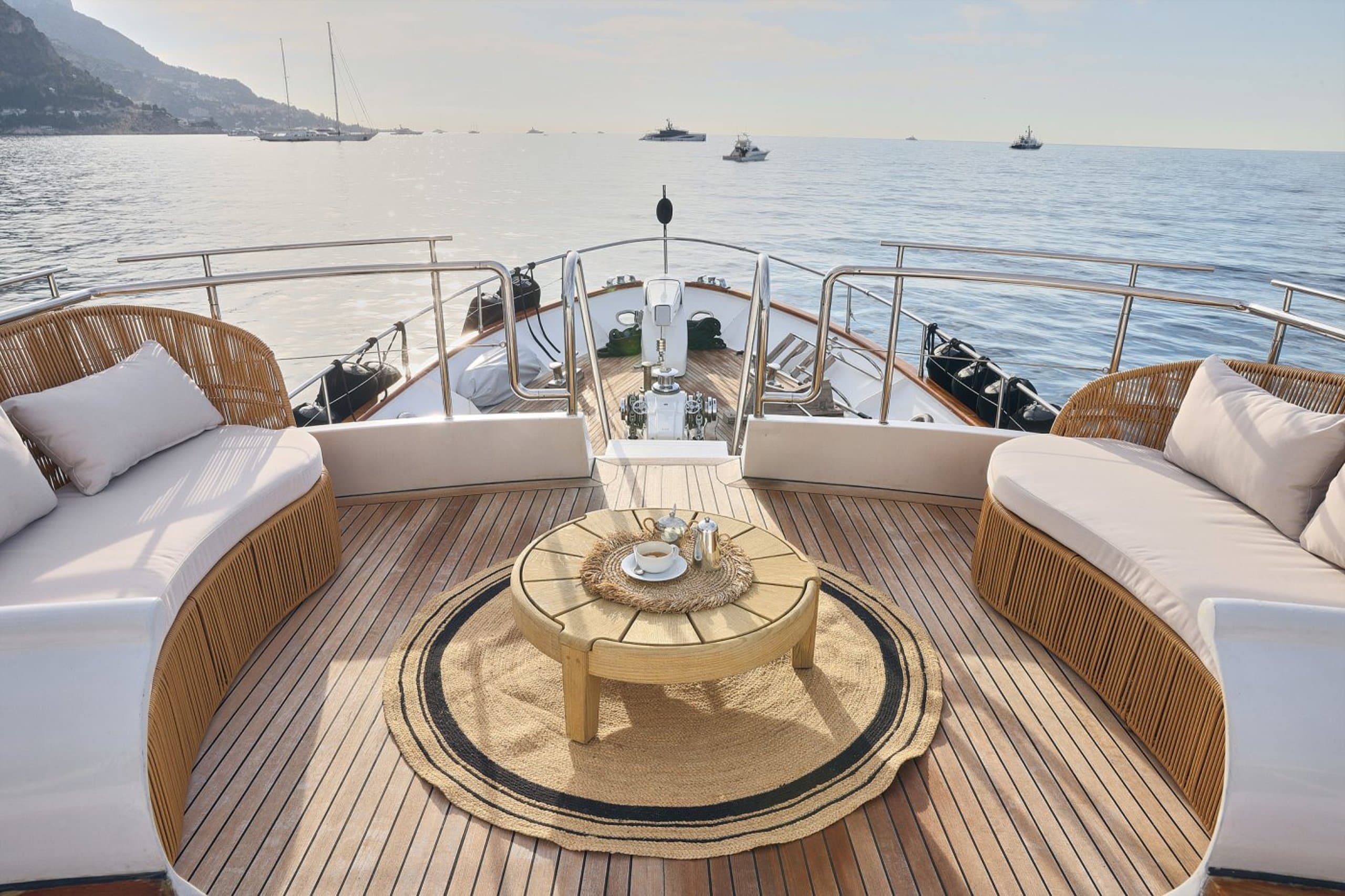 SOUNION II - foredeck seating area with curved wicker sofas, round teak table and coffee service | Drivas Yachts