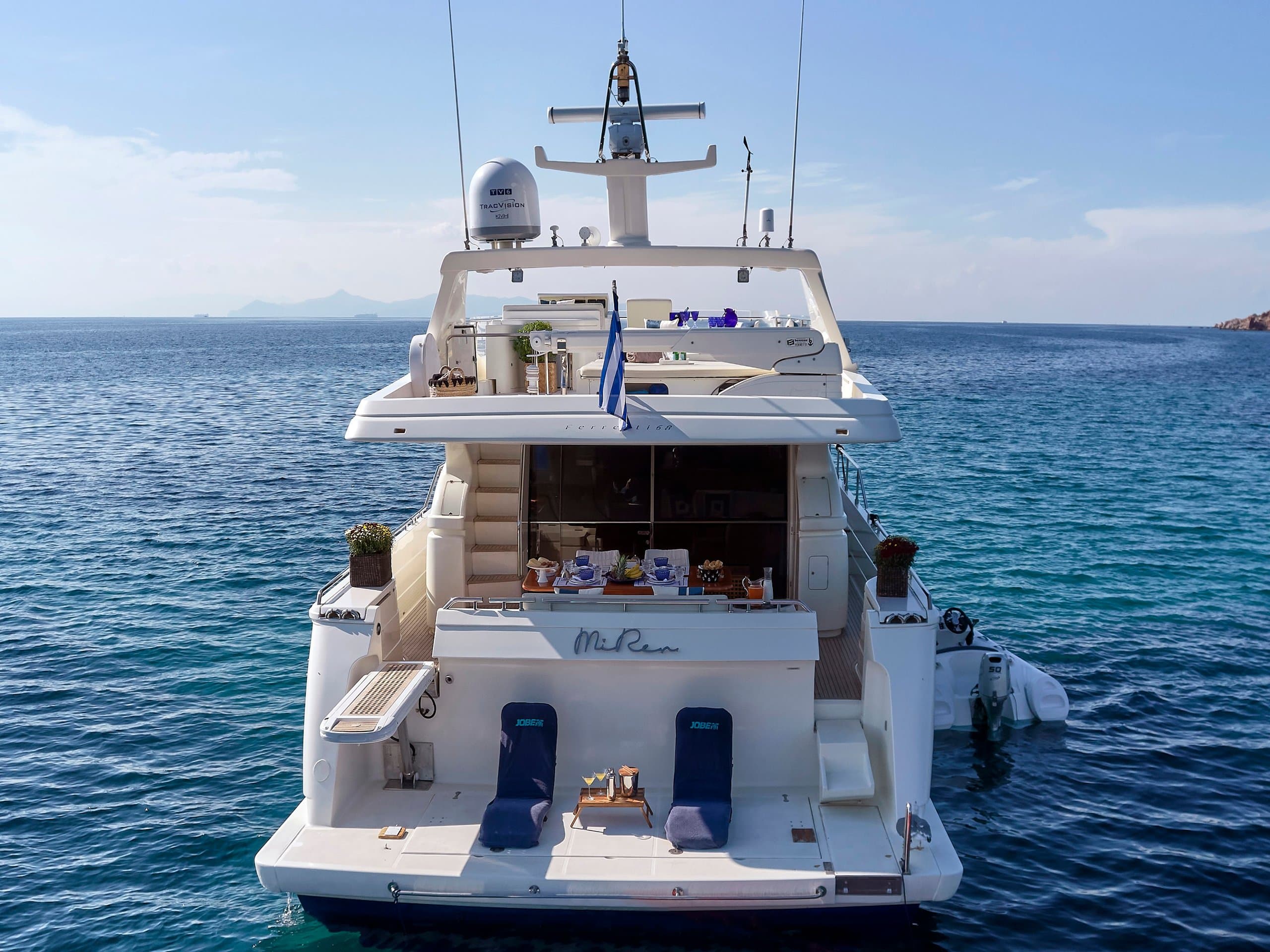 MIREN - stern view showing the aft deck, flybridge and MiRen name on the transom, at anchor near a coastline | Drivas Yachts
