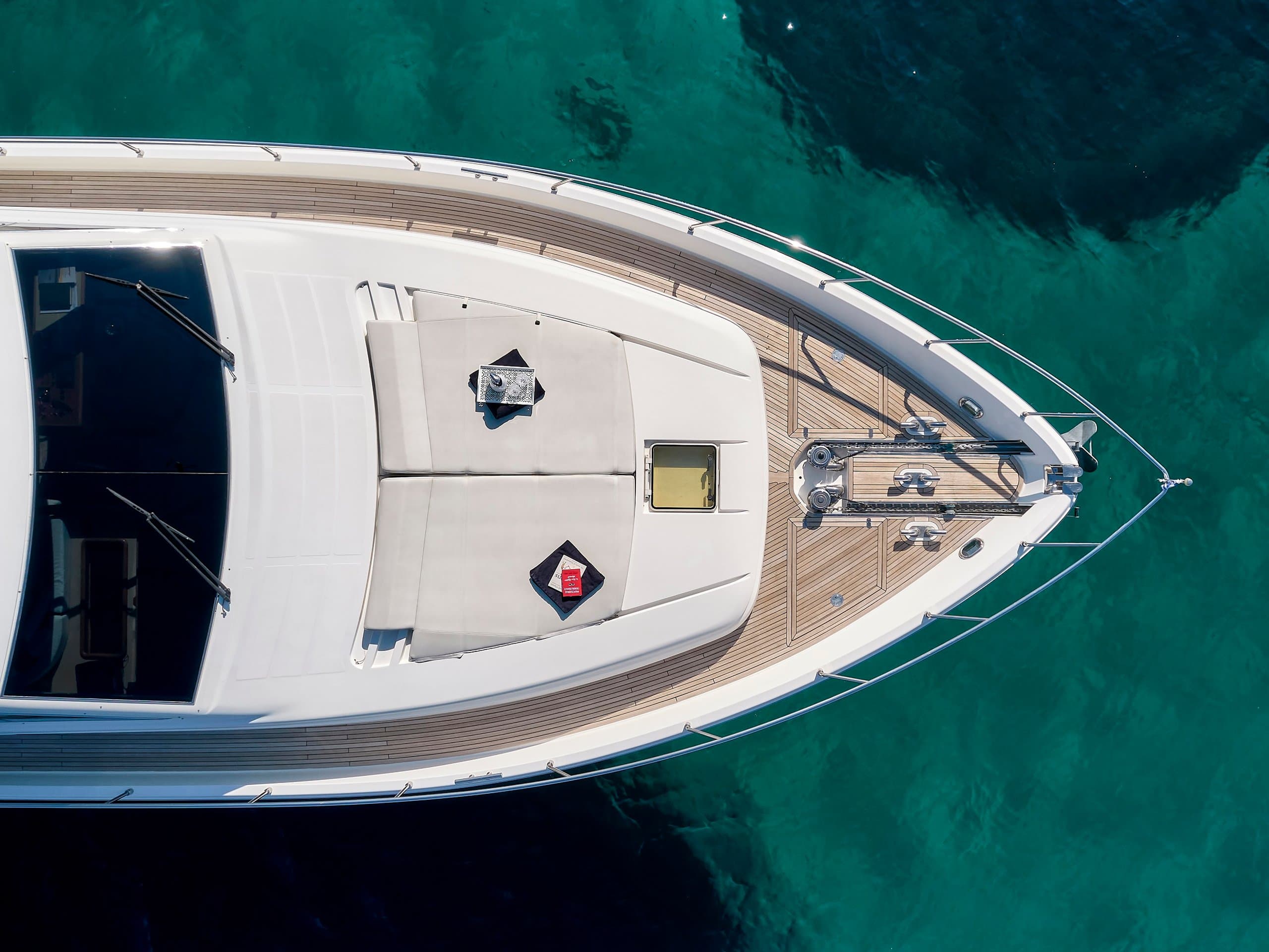 MIREN - aerial view of the bow, forward sunpads and teak side decks over clear green water | Drivas Yachts