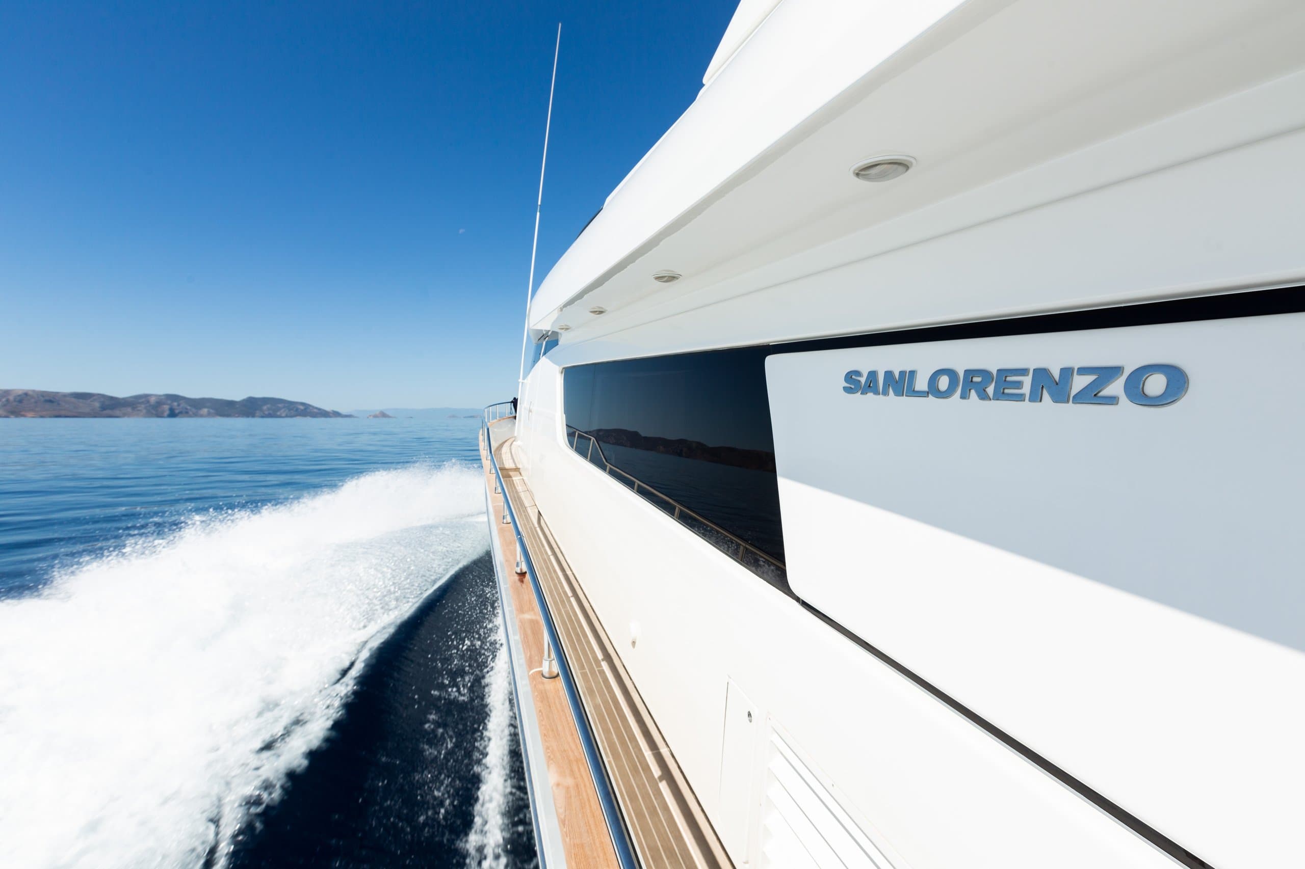 ALEGRIA - hull side view of the yacht underway, wake and coastline beyond | Drivas Yachts