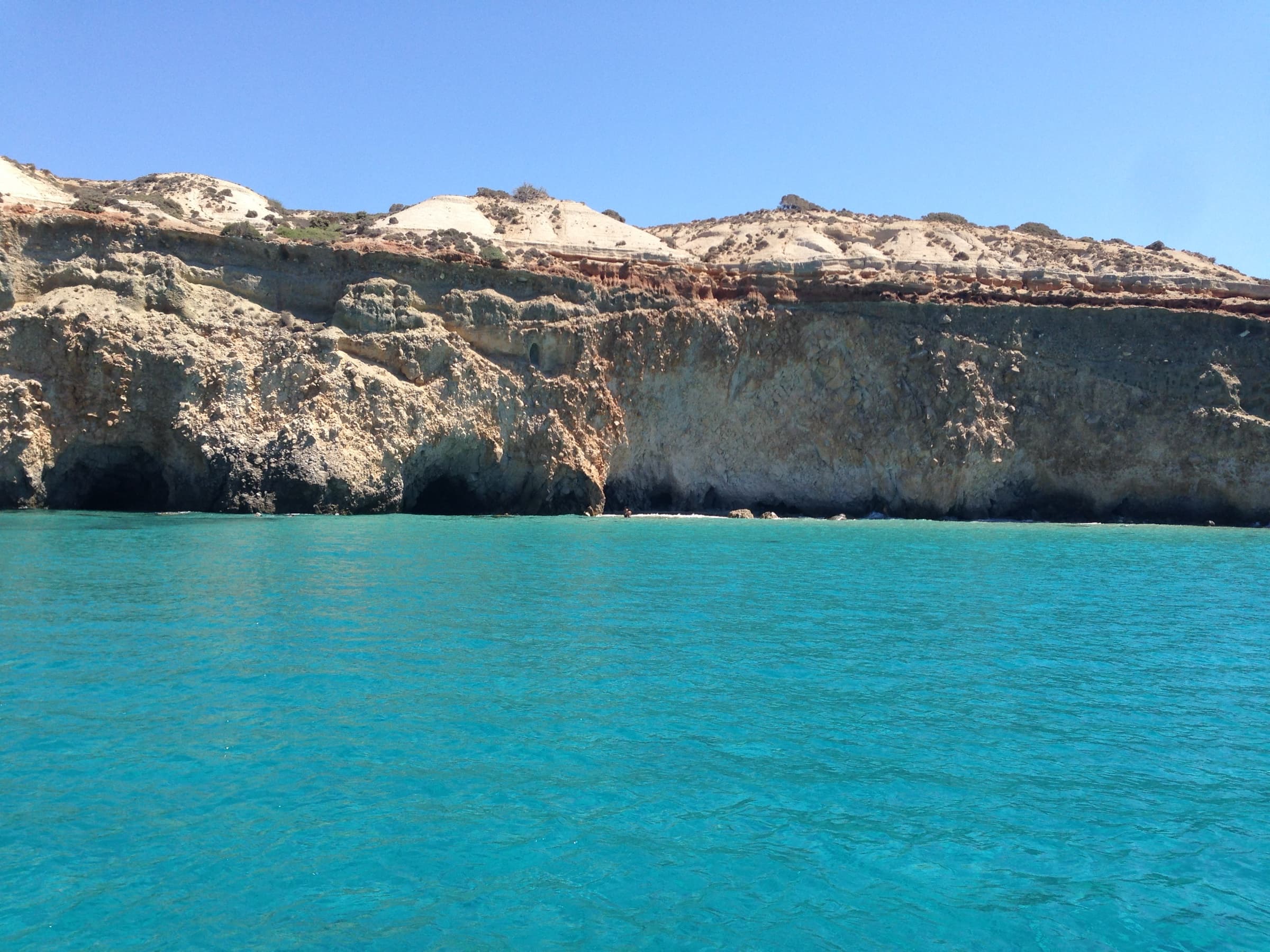 The volcanic coastline of Milos above turquoise water