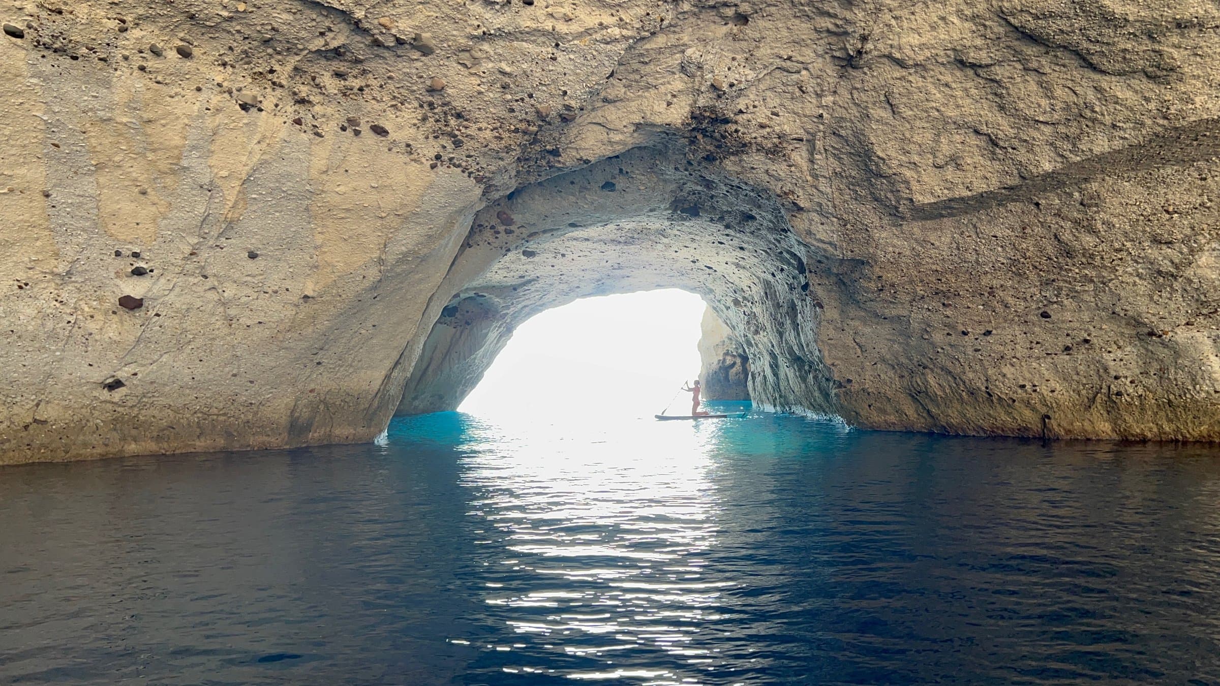 A paddleboarder inside a sea cave near Kleftiko, Milos